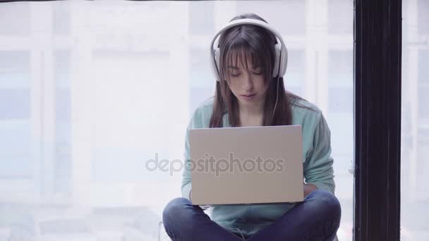 Woman in headphones working on a laptop — Stock Video