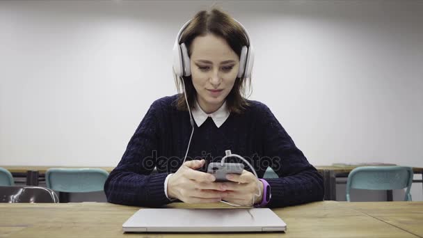 Femme dans les écouteurs tourne un téléphone intelligent — Video