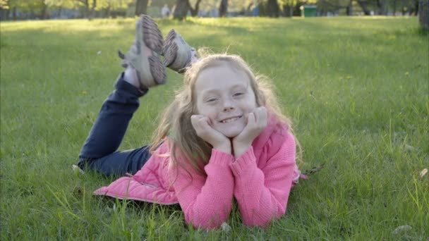 Дівчина лежить на траві і посміхається — стокове відео