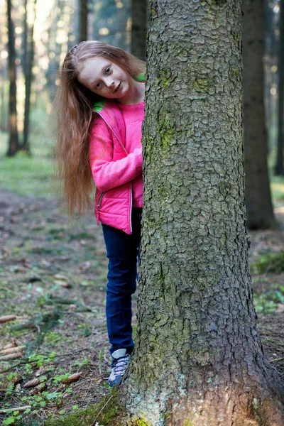 Ormandaki bir ağaç arkasından küçük kız görünüyor