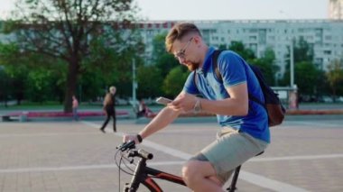 adam bir bisiklet sürmek ve bir akıllı telefon kullanır