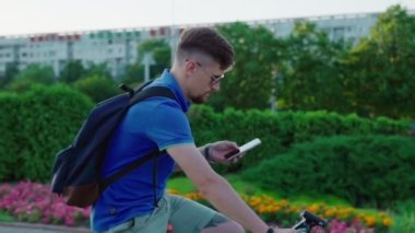 adam bir bisiklet sürmek ve bir akıllı telefon kullanır