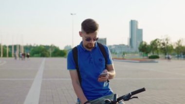 adam bir bisiklet sürmek ve bir akıllı telefon kullanır