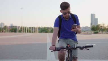 bir akıllı telefon tutarak ve bir bisiklet sürme hipster adam