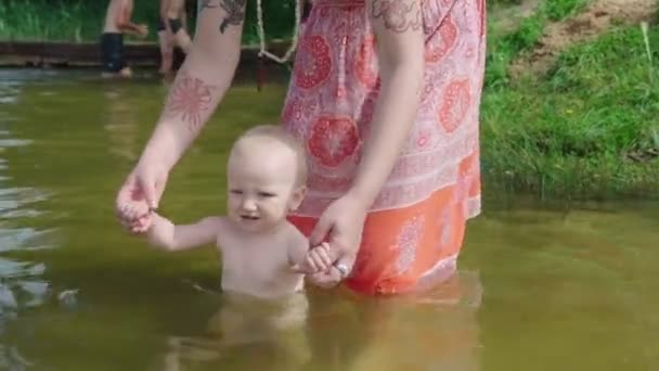 Moeder baadt de baby in de vijver — Stockvideo