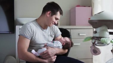 Babası yeni doğan bebek kollarında tutar.