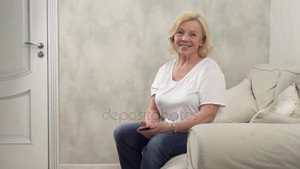 Щаслива старша жінка сидить на дивані — стокове відео