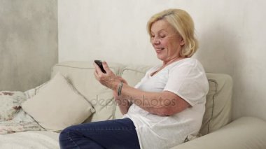 Mutlu yaşlı kadın bir akıllı telefon kullanır
