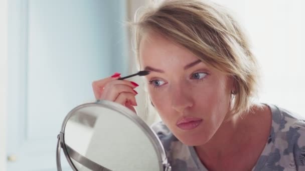 Erwachsene Frau beim Make-up, korrigiert Augenbrauen — Stockvideo