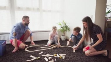 Anne ve baba çocuklarının oyuncak tren yolu oluşturmak için yardım