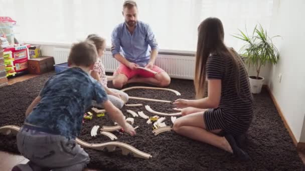 Bambini e genitori insieme costruiscono una ferrovia giocattolo — Video Stock