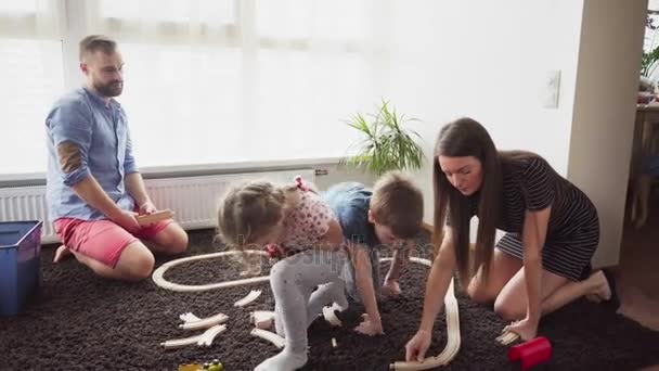 Parents help their children to build a toy railroad — Stock Video