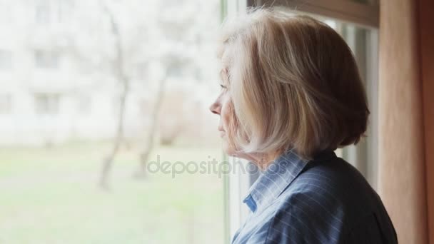 Mujer mayor mirando por la ventana — Vídeo de stock