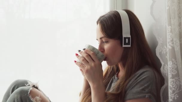 Vrouw zitten op een vensterbank en een warm drankje — Stockvideo