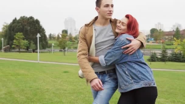 Uomo e donna felici camminano e si abbracciano nel parco della città — Video Stock