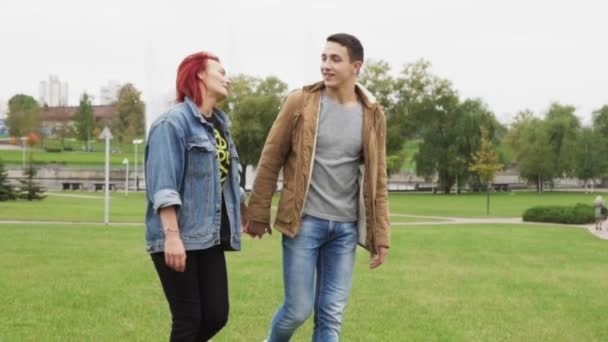 Un joven abraza y besa a su novia mientras camina por el parque de la ciudad — Vídeo de stock