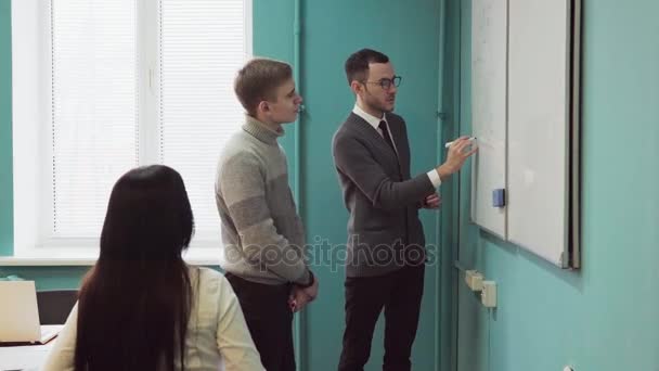 Professor explica algo em um quadro branco para os alunos — Vídeo de Stock