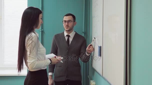 Homem e mulher conduzem uma reunião de negócios perto do quadro branco — Vídeo de Stock