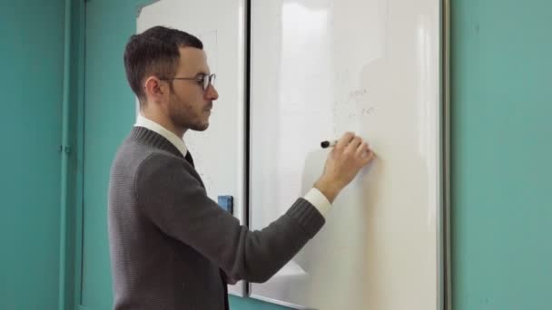 Man teacher writes on white board in class room — Stock Video