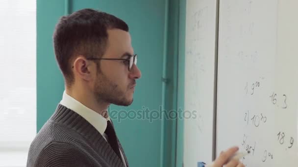 Närbild av en skäggig man med glasögon skriva på whiteboard — Stockvideo