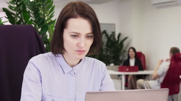 Ділова жінка працює на ноутбуці і п'є каву в офісі — стокове відео
