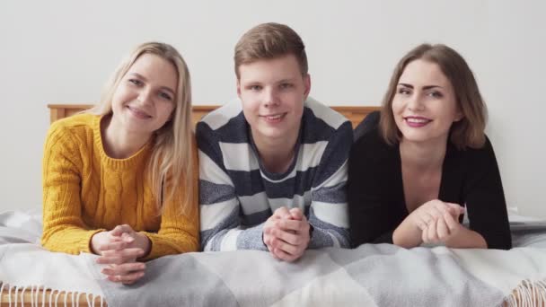 Group of happy teenagers lying on bed and smiling — Stock Video