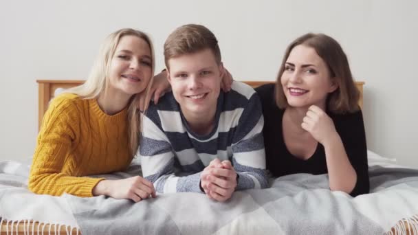 Duas meninas abraçando um amigo e sorrindo na cama — Vídeo de Stock