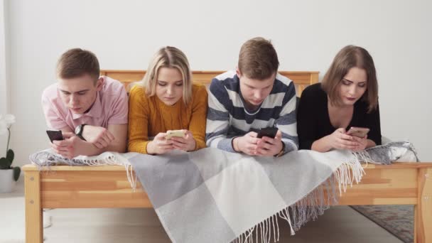 Los adolescentes están acostados en la cama y usando teléfonos inteligentes — Vídeos de Stock