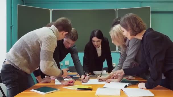 Студенты вместе с преподавателем работают над проектом в университете — стоковое видео