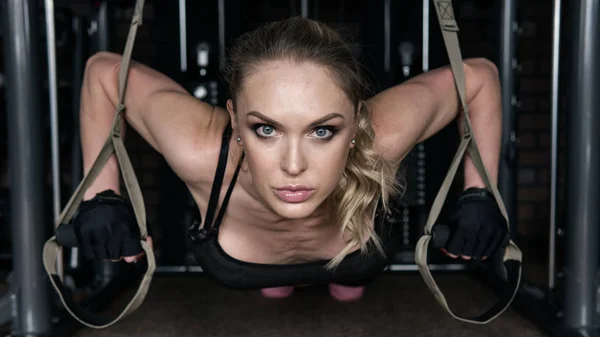 Mujer fitness realiza flexiones en bucles de suspensión en el gimnasio —  Fotos de Stock