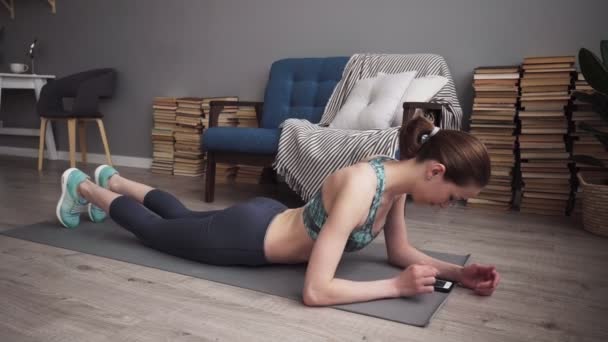 Kobiety fitness w domu za pomocą smartfona i robienie ćwiczeń deski — Wideo stockowe
