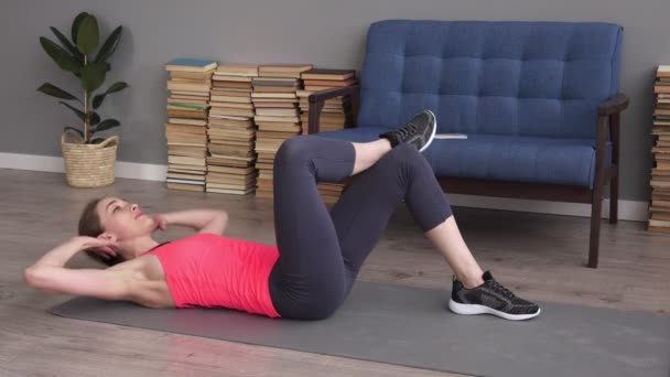 Mujer de fitness haciendo ejercicios abdominales en la esterilla en casa — Vídeo de stock