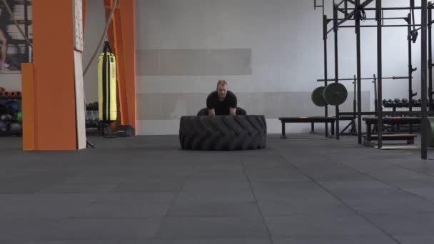 Hombre de fitness haciendo grandes volteretas de neumáticos ejercicio en el gimnasio — Vídeos de Stock