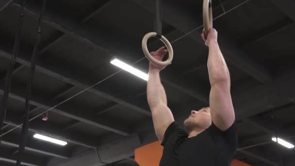 Stark man gör ringar muscle ups övning i cross fit gym — Stockvideo