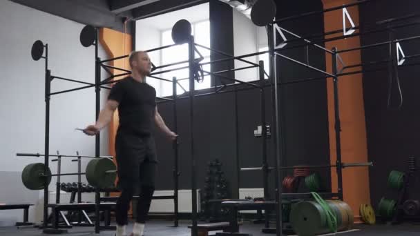Фитнесмен делает двойные прыжки канат упражнения в тренажерном зале, панорамный снимок — стоковое видео