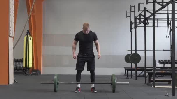 Чоловік-спортсмен робить вправи з барбелла в хрестоподібному спортзалі — стокове відео