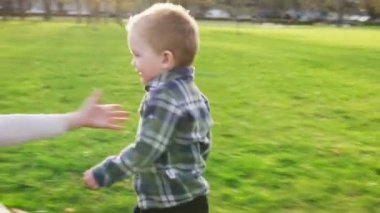 Sevimli küçük oğlu sarılma ve parkta günbatımında gülümseyen annesine çalışır