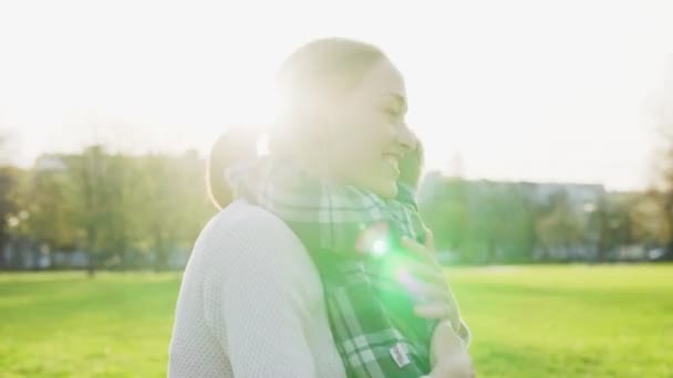 Ευτυχισμένη μητέρα αγκαλιάζει και απαλά περιγράμματα το μικρό παιδί στο ηλιοβασίλεμα στο πάρκο — Αρχείο Βίντεο
