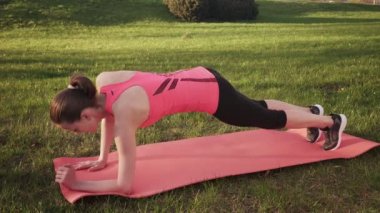 Fitness kadının gün güneşli yaz çimen, dinamik tahta egzersiz yapması