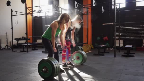 Zespół dwóch kobiet fitness szkolenia martwy ciąg, dając piątkę w siłowni — Wideo stockowe