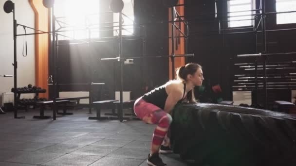 Mujer fuerte fitness haciendo grandes volteretas de neumáticos entrenamiento en el gimnasio — Vídeo de stock