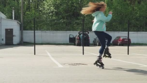 Молодая женщина умело кружится на роликовых коньках по асфальтовой дороге — стоковое видео