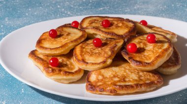 Taze krepler beyaz bir tabakta yatar. Kreplerin üzerinde taze böğürtlen var.