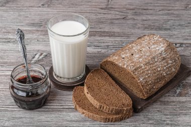 Bir bardak süt ve bir kavanoz reçelin yanında çavdar ekmeği.