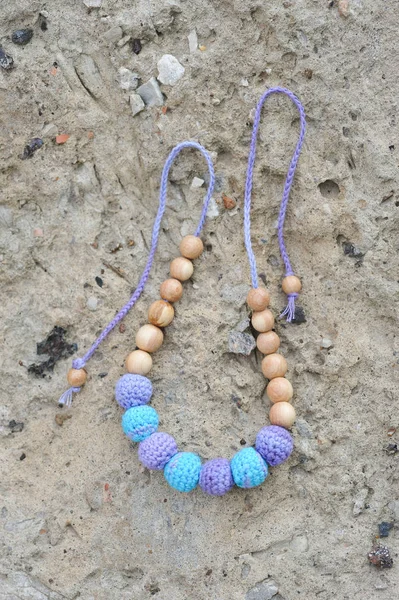 Necklace made from knitted beads on the stone background.