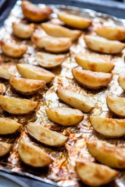 Altın kahverengiye kadar fırında folyoyla pişirilmiş patates dilimleri..