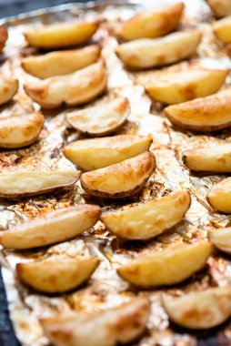 Altın kahverengiye kadar fırında folyoyla pişirilmiş patates dilimleri..