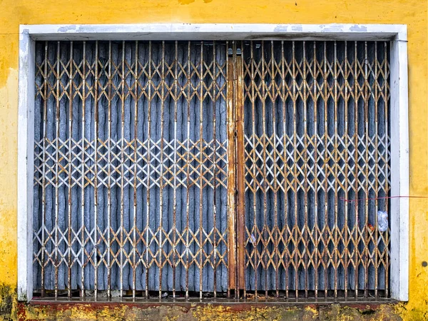Gruñona oxidada puerta de metal azul y amarillo —  Fotos de Stock
