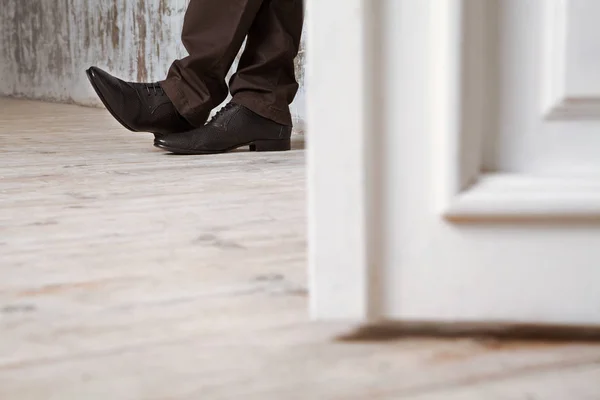 Człowiek w czarne buty na drewnianą podłogę. — Zdjęcie stockowe