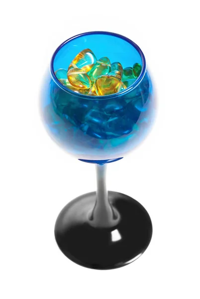 Pietre gialle ambrate nel bicchiere blu per il vino . Fotografia Stock